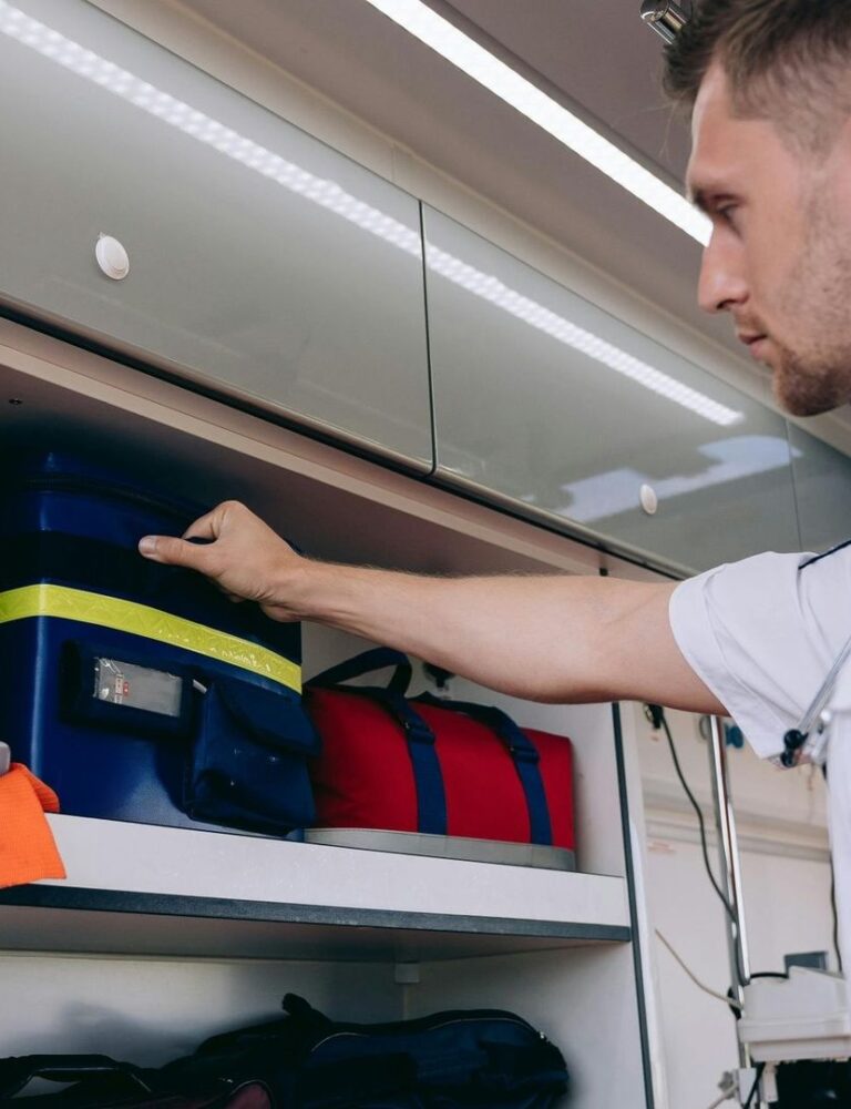 Emergency responder retrieves medical bags from an ambulance storage compartment